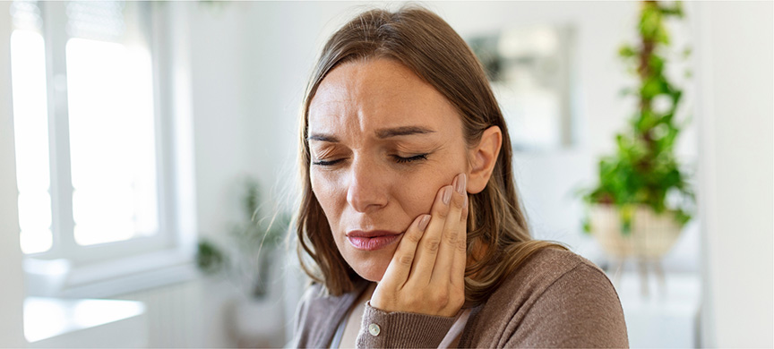 Woman holding her cheek wincing